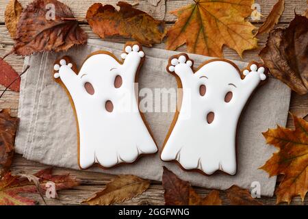 Halloween Lebkuchen und Herbstblätter auf Holzplanken, weiße Geister Stockfoto