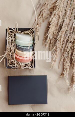 Handgefertigte runde Naturseifen in schwarzer Geschenkbox. Draufsicht, Pastellfarben. Natürlich. Stockfoto