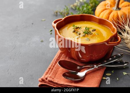 Kürbissuppe mit Thymian und Kürbiskernen auf schwarzem Hintergrund Stockfoto