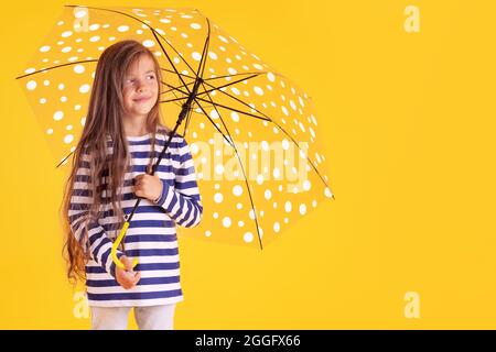Glücklich emotionale Mädchen lachen mit Regenschirm auf farbigem gelben Hintergrund. Herbst, Frühjahrssaison. Stockfoto
