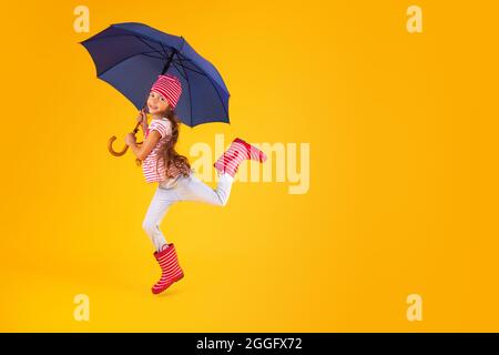 Glücklich emotionale Mädchen lachen mit Regenschirm auf farbigem gelben Hintergrund. Herbst, Frühjahrssaison. Stockfoto