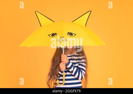 Glücklich emotionale Mädchen lachen mit Regenschirm auf farbigem gelben Hintergrund. Herbst, Frühjahrssaison. Stockfoto