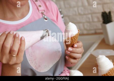 Konditor, der mit dem Konditorei Eiscreme für Marschmarmeleien macht, Nahaufnahme Stockfoto