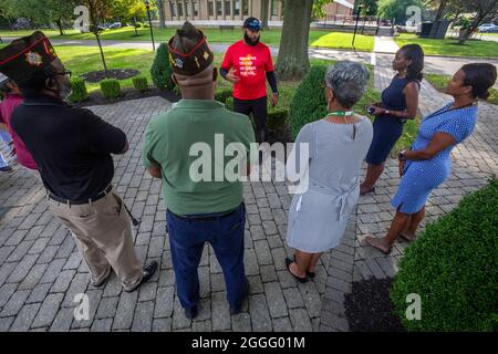 Greg C. Washington, II, in der Mitte mit rotem Hemd, spricht das New Jersey Department of Military and Veterans Affairs und die Mitglieder der Veteranen-Organisation in Lawrenceville, N.J., 31. August 2021 an. Washington, ein Absolvent der United States Military Academy und ehemaliger Armee-Infanterie-Kapitän, der sowohl in Afghanistan als auch im Irak diente, läuft 1,800 Meilen, um auf die wachsende Zahl von Veteranen-Selbstmorden aufmerksam zu machen. In einem Bericht des US-amerikanischen Veteranenministeriums aus dem Jahr 2019 heißt es, dass zwischen 2008 und 2017 mehr Veteranen Selbstmord begingen und dann im Vietnamkrieg starben. Washington begann seinen 11-Staaten-Walk to Honor in Mou Stockfoto