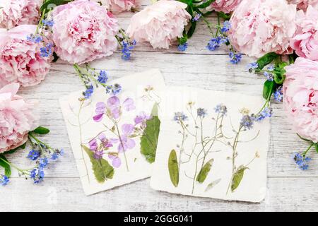 Handgemachte Postkarte mit getrockneten, gepressten Blumen und frischen rosafarbenen Pfingstrosen. Retro-Style Stockfoto