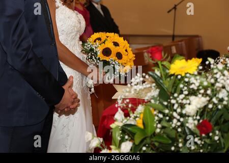 Brautpaar in der Kirche mit einem Blumenstrauß während der Zeremonie in der Kirche Stockfoto