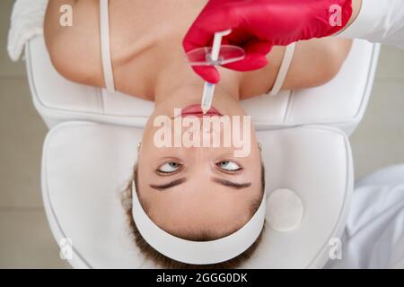 Kosmetikerin macht Injektion in der Nase mit Spritze im Schönheitssalon. Kosmetische verjüngende Gesichtsbehandlung Stockfoto