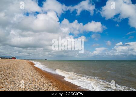 Walmer Beach in Kent blickt zurück auf den Pier an einem Sommertag mit blauem Himmel und weißen Wolken Stockfoto