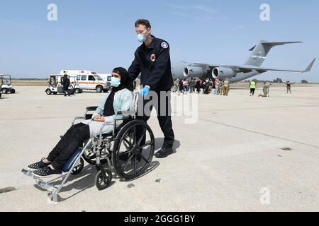 Rota, Spanien. Januar 2016. Eine afghanische Frau wird bei der Ankunft nach der Evakuierung aus Afghanistan auf der Naval Air Station Rota am 27. August 2021 in Rota, Spanien, unterstützt. NAS Rota stellt im Rahmen der Operation Allies Refuge eine temporäre Unterkunft für Evakuierte aus Afghanistan bereit.Quelle: MC2 Katie Cox/U.S. Navy/Alamy Live News Stockfoto