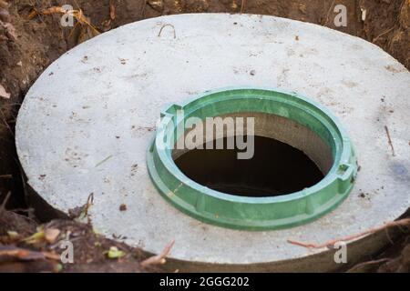 Bau einer Klärgrube. Große Betonringe in den Boden eingebettet, von oben eine offene Kanalluke, ungeschützt durch eine Abdeckung vor Herunterfallen. Stockfoto