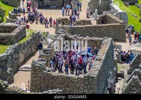 MACHU PICCHU, PERU - 18. MAI 2015: Besuchermassen im Haus des Hohenpriesters in den Ruinen von Machu Picchu, Peru. Stockfoto