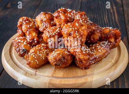 Knusprig orange glasierte Hähnchenflügel auf dem Holzbrett Stockfoto
