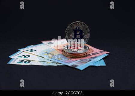 Bitcoins auf 20 und 10 Euro Banknoten. Bitcoins auf zehn- und zwanzig-Euro-Banknoten auf dunklem Hintergrund. Stockfoto