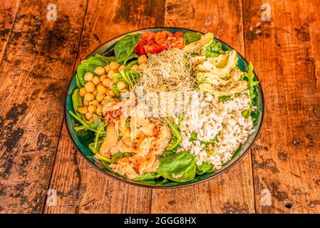 Poke Schüssel mit norwegischem Lachs, Spinat, gekochten Kichererbsen, Arrob, Avocado, Stücke von Kirschtomaten, Rucola und Bohnensprossen Stockfoto