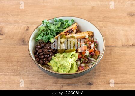 Tolle mexikanische Schüssel mit gegrilltem Hähnchen, Pico de gallo, Guacamole, schwarzen Bohnen, grünem Grünkohl und Jalapenos auf Basis von weißem Reis Stockfoto