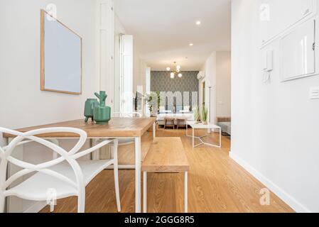 Studio-Apartment mit minimalistischem Dekor mit Esstisch im Vordergrund und Schlafzimmer im Hintergrund in einer Ferienwohnung Stockfoto