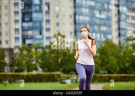 Frau in schützender Gesichtsmaske läuft im Freien. Stockfoto