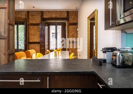 Blick von der Küche auf ein Wohnzimmer in einem Vintage-Gebäude mit Backsteinmauer in einer Ferienwohnung gesehen Stockfoto