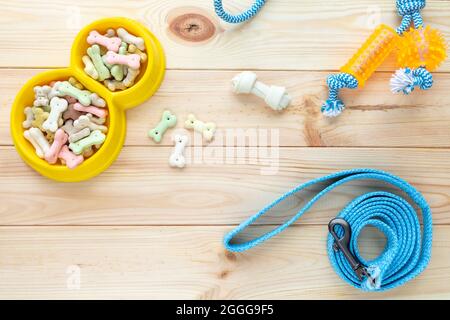 Verschiedene bunte Tierpflegezubehör: Ring, Knochen, Kugeln, Snacks auf natürlichem Holzhintergrund. Gummi- und Textilzubehör für Hunde. Stockfoto