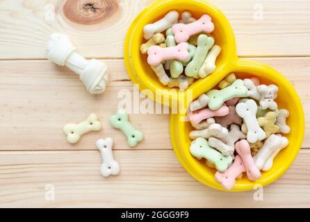 Verschiedene bunte Tierpflegezubehör: Ring, Knochen, Kugeln, Snacks auf natürlichem Holzhintergrund. Gummi- und Textilzubehör für Hunde. Stockfoto