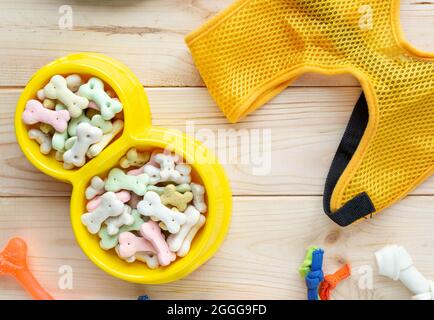 Verschiedene bunte Tierpflegezubehör: Ring, Knochen, Kugeln, Snacks auf natürlichem Holzhintergrund. Gummi- und Textilzubehör für Hunde. Stockfoto