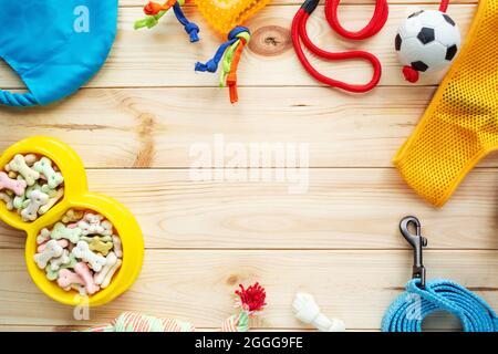 Verschiedene bunte Tierpflegezubehör: Ring, Knochen, Kugeln, Snacks auf natürlichem Holzhintergrund. Gummi- und Textilzubehör für Hunde. Stockfoto