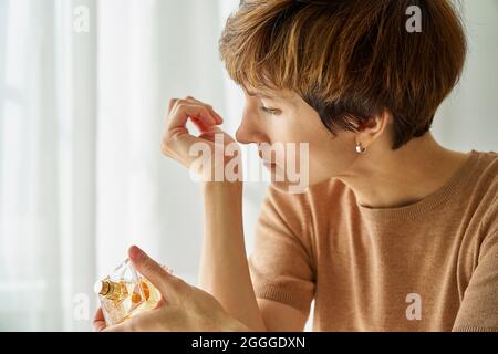 Frauen schnüffeln am Handgelenk und prüfen selbst, ob sars-COV-2 vorhanden ist. Lang anhaltendes kovidhaftes Beschwerden Stockfoto