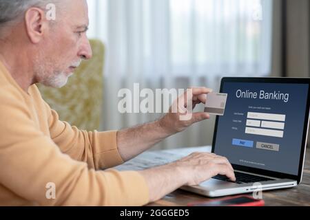 Ein Mann, der ein Smartphone und eine Kreditkarte in der Hand hält Stockfoto