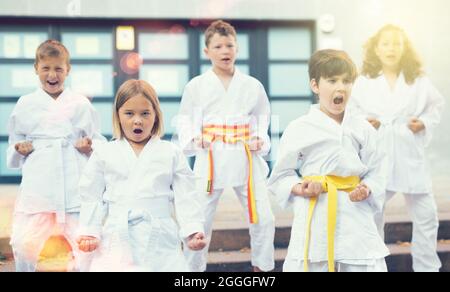 Gruppe von Jugendlichen Kindern, die Karate-Bewegungen auf dem Schulhof lernen Stockfoto