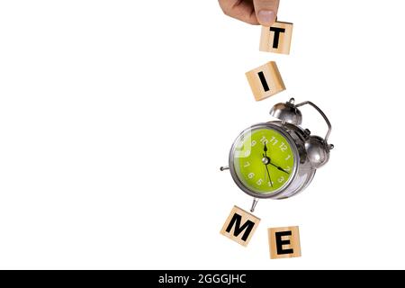 Eine Hand, die einen herunterfallenden rostigen alten Wecker und vier Holzwürfel mit der Schreibweise „Zeit“ anfängt. Levitation Photography, „Time“-Konzept. Stockfoto