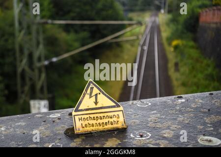 Burg Stargard, Deutschland. August 2021. Auf einer Brücke über Bahngleise in Burg Stargard steht ein Schild mit der Aufschrift „Hochspannungs-Gefahr für das Leben“. Quelle: Kira Hofmann/dpa-Zentralbild/dpa/Alamy Live News Stockfoto