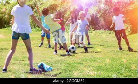 Fröhliche Kinder joggern und spielen Fußball im Park Stockfoto