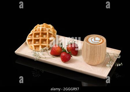 Waffeln mit frischen Erdbeeren und einer Tasse Cappuccino. Stockfoto