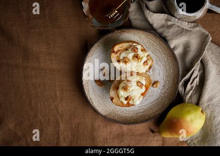 Gegrillte süße Birnen mit Nüssen und Honig. Serviert auf braunen Tischdecken im Herbst Dessert Stockfoto