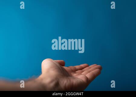 Nahaufnahme eines Männchens zeigt ausgestreckte Hand isoliert auf blauem Hintergrund Stockfoto