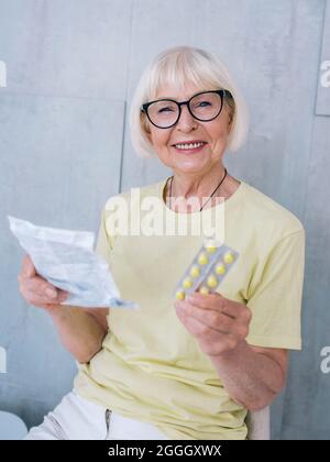 Ältere lächelnde Frau mit Pillen in der Hand. Gesundheitswesen, Medizin, Behandlung, Alterskonzept Stockfoto