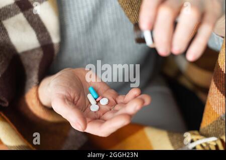 Eine Hand einer älteren Frau hält verschiedene Tabletten und Pillen, Nahaufnahme Medikamente auf der weiblichen Handfläche. Behandlungskonzept, Vitamine für ältere Menschen für Gesundheit und Wohlbefinden Stockfoto