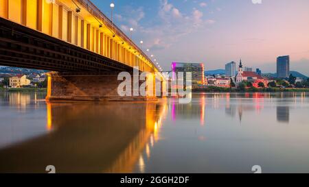 Linz, Österreich. Stadtbild des Flussufers Linz, Österreich bei Sonnenaufgang im Sommer mit Spiegelung der Lichter der Stadt in der Donau. Stockfoto