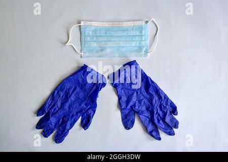 Ein Paar blaue medizinische Einweghandschuhe aus Latex und eine Maske auf hellem Hintergrund. Virenschutzmittel. Draufsicht. Nahaufnahme. Selektiver Fokus. Stockfoto