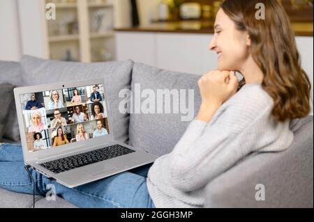 Virtuelle Treffen mit einer Gruppe von verschiedenen Menschen, junge Frau froh, Freunde online auf der Ferne zu treffen, Laptop-Bildschirm mit vielen multirassischen Kollegen beteiligt Videokonferenz Stockfoto