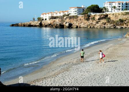 Blick auf Menschen, die am ruhigen Strand entlang laufen, Nerja, Spanien. Stockfoto