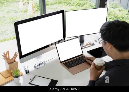 Geschäftsmann trinkt Kaffee und arbeitet mit mehreren modernen Geräten. Stockfoto