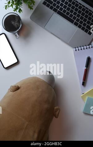 Teddybär, Laptop-Computer und Smartphone auf weißem Schreibtisch. Stockfoto