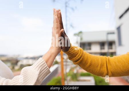 Vielfältige männliche und weibliche Kollegen bei der Arbeit, High-Fiving Stockfoto