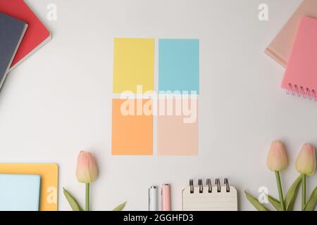 Bunte Haftnotizen, rosa Tulpen und Notizbuch auf weißem Hintergrund. Stockfoto