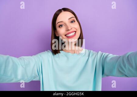 Foto Porträt Mädchen tragen blauen Pullover lächelnd glücklich unter Selfie isoliert pastellvioletten Hintergrund Stockfoto