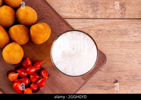 Traditioneller brasilianischer frittierter Snack mit Huhn, bekannt als „Coxinha“, und Paprika mit kleinem Schnabel, Brasilien, genannt „Pimenta Biquinho“. Stockfoto