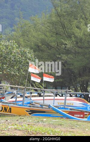PACITAN, INDONESIEN - 22. August 2021: Ein Fischerboot mit rot-weißer Flagge am Strand von Teleng Ria Pacitan, Ost-Java Stockfoto