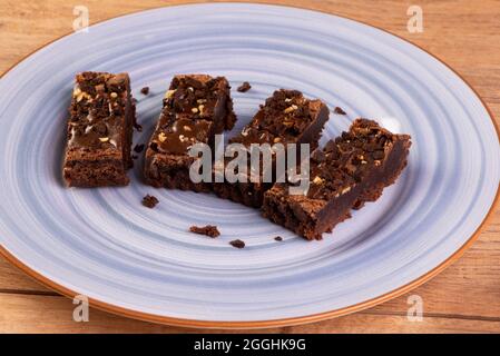 Einige Brownie-Scheiben auf einem blauen Teller auf einem Holztisch. Stockfoto