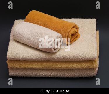 Weiße und gelbe saubere Handtücher auf dunkelgrauem Hintergrund. Massage, Spa, Hotelkonzept. Stockfoto